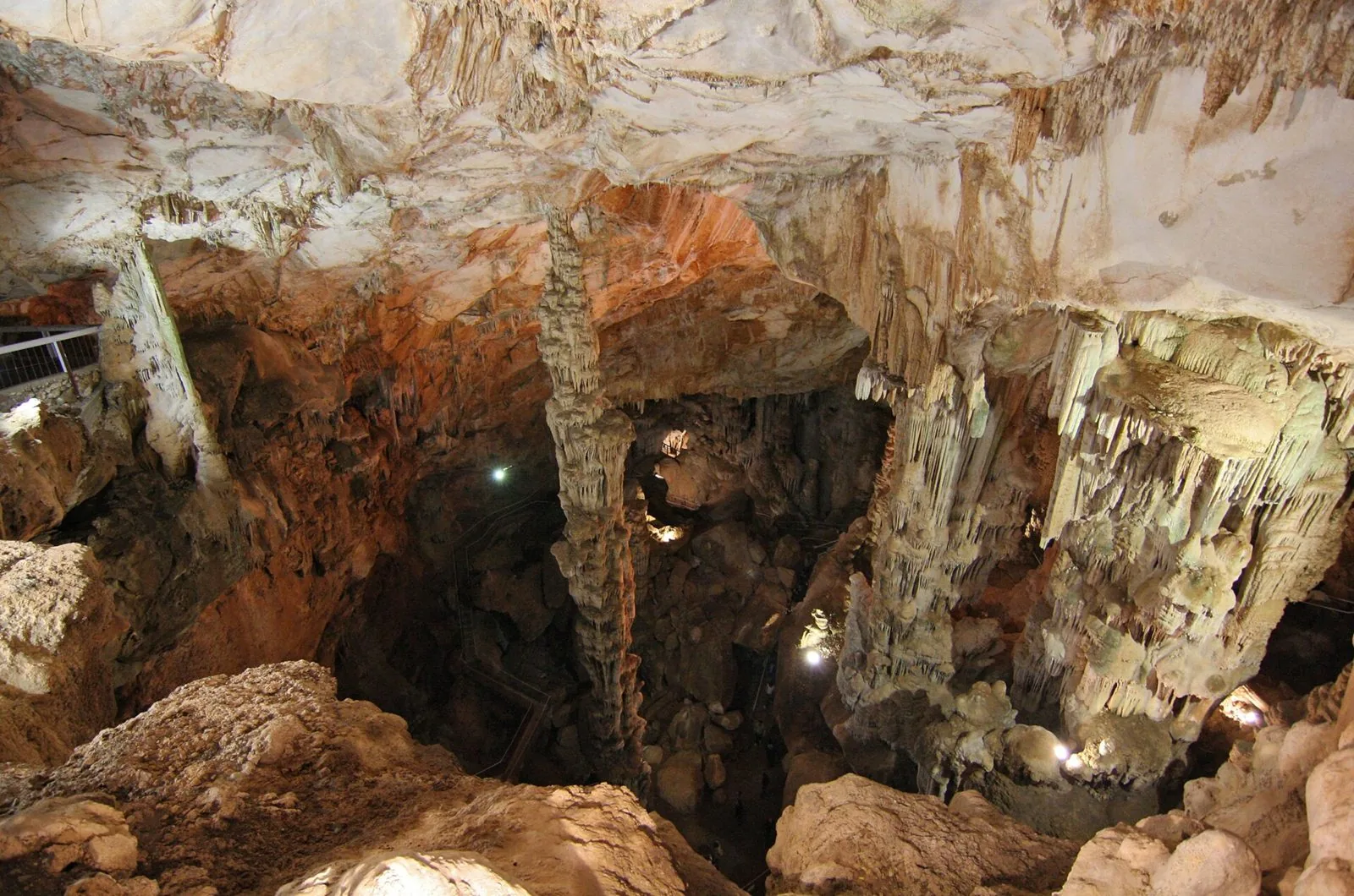 Interno della Grotta di Ispinigoli con grandi stalattiti e stalagmiti illuminate e la scala che scende nella sala
