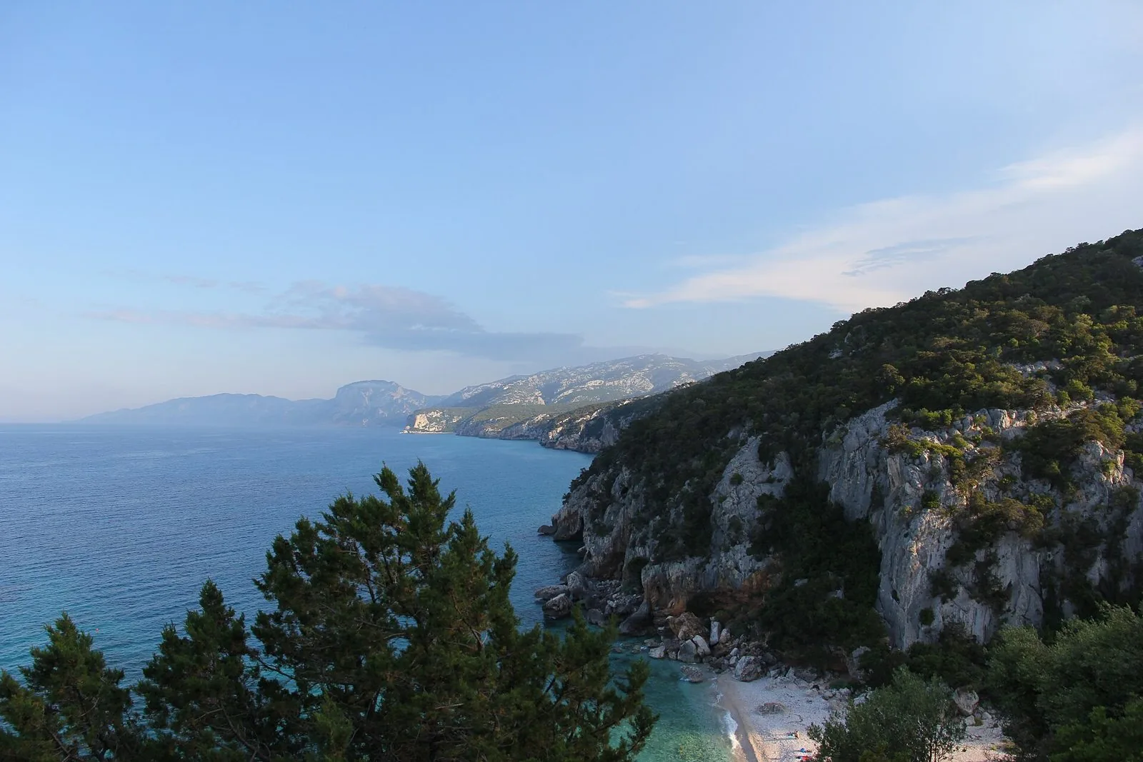 Falesie calcaree ricoperte di macchia mediterranea che scendono su una piccola spiaggia bianca e sul mare turchese
